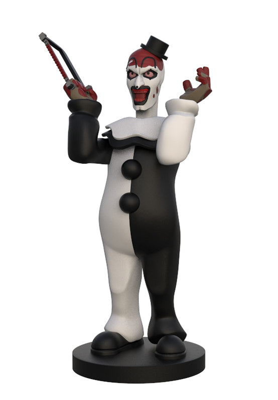 A stylized horror clown figurine standing on a round black base, wearing a black-and-white suit, red face paint, and holding a chainsaw in one hand, photographed on a plain white background.