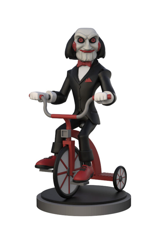 A stylized collectible figure of a skeletal character with red eyes riding a red tricycle on a round black base, shown against a plain white background.